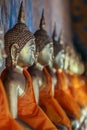 Left side view of a row of golden Buddhas statues seated along the wall wrapped in orange cloth. Royalty Free Stock Photo