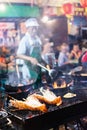 Bangkok, Thailand - March 2019: man cooking seafood at the Chinese night market street restaurant