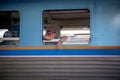 Bangkok, Thailand - March 6th 2020: Passenger gazing out a window of a train in Bangkok Railway Station