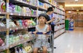 BANGKOK THAILAND - MARCH 24: Unidentified boy stares in boredom on a shopping cart as the mother shops in Foodland supermart in