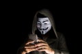 Bangkok, Thailand - May 6, 2018 : A hacker wears a mask wearing a robe. using smartphone theft and attacking data on cyberspace.