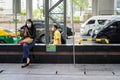 BANGKOK, THAILAND - MAY 10, 2020 - Woman sitting outdoors while wearing facial mask and using mobile phone during corona