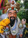 Sculpture of a man with a child in his arms with pearls and flowers deposited as an offering at the Pig Memorial. Bangkok Pig Mon