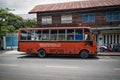 Old orange retro bus parking on the side of a quiet street of Bangkok