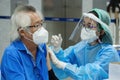 Bangkok, Thailand - September 17, 2021 : asian doctor or nurse giving covid antivirus vaccine shot to senior man patient wearing