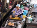 A man grills chicken on the barbecue of his boat at the Taling Chan Floating Market in Bangkok