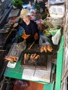 A woman cooks in her boat at the Taling Chan Floating Market in Bangkok