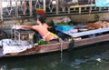 A woman grills fish on the barbecue of her boat at the Taling Chan Floating Market in Bangkok