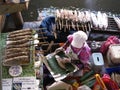 A woman grills fish in the kitchen of her boat at the Taling Chan Floating Market in Bangkok