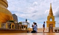 Bangkok Thailand. Young couple praying in front of big golden buddah temple in urban mountain temples site with t