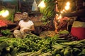 Bangladeshi greengrocer in stall on indoor market