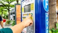 Unidentified man using the parking ticket payment machine at the side of the road