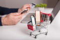 Bank card nearby a laptop and mini shopping cart on white backg Royalty Free Stock Photo