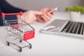 Bank card nearby a laptop and mini shopping cart on white background top view Royalty Free Stock Photo