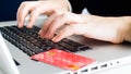 Bank credit card lying on laptop next to female hands typing on keyboard. Concept of online shopping and e-commerce Royalty Free Stock Photo