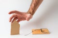 Bank investments and mortgages. Male hand reaching for the cardboard house, lying next to the trap.White background. Copy space