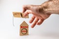 Bank investments and risks. A man`s hand caught in a mousetrap, there is a cardboard schematic house with the inscription BANK