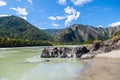 The bank of the Katun river with water containing turquoise clay and a sandy beach, rocky coast against the backdrop of mountains Royalty Free Stock Photo