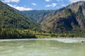 The bank of the Katun river with water containing turquoise clay and a sandy beach, rocky coast against the backdrop of mountains Royalty Free Stock Photo