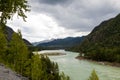 The bank of the Katun river with water containing turquoise clay and a sandy beach, rocky coast against the backdrop of mountains Royalty Free Stock Photo