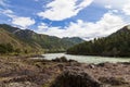 The bank of the Katun river with water containing turquoise clay and a sandy beach, rocky coast against the backdrop of mountains Royalty Free Stock Photo