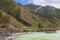 The bank of the Katun river with water containing turquoise clay and a sandy beach, rocky coast against the backdrop of mountains Royalty Free Stock Photo