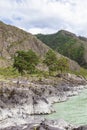 The bank of the Katun river with water containing turquoise clay and a sandy beach, rocky coast against the backdrop of mountains Royalty Free Stock Photo