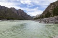 The bank of the Katun river with water containing turquoise clay and a sandy beach, rocky coast against the backdrop of mountains Royalty Free Stock Photo