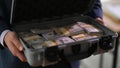 Banker holding suitcase with many dollar bills closeup