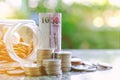 Banknote and coins in and outside the glass jar, Thai Baht currency on blurred natural green background Royalty Free Stock Photo