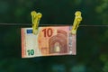 The banknote is hung on two clothespins for drying on a rope. Blurred dark green background. There is money laundering Royalty Free Stock Photo