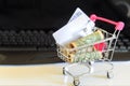 Banknote roll in pink mini shopping cart on white table with key Royalty Free Stock Photo