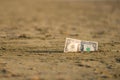 Banknote of value of one dollar in the the sand on the beach. Concept of cheap travel and vacation. Royalty Free Stock Photo