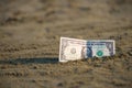 Banknote of value of one dollar in the the sand on the beach. Concept of cheap travel and vacation. Royalty Free Stock Photo