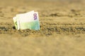 Banknote of value of one hundred euro in the the sand on the beach. Concept of cheap travel and vacation.