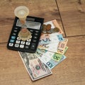 Banknotes and coins of the Republic of Belarus, fifty US dollars, an hourglass and a calculator on a wooden background. Royalty Free Stock Photo