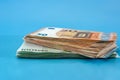 Banknotes in denominations of 50 and 100 euros isolated on a blue background. Much money. Stacks with euro banknotes. Financial co