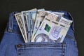 Banknotes of different denominations in the pocket of women`s jeans, background. Concept, American dollars and Ukrainian hryvnias