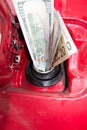 Banknotes, dollars in the fuel filler of a red car Royalty Free Stock Photo