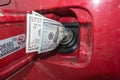 Banknotes, dollars in the fuel filler of a red car Royalty Free Stock Photo