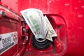 Banknotes, dollars in the fuel filler of a red car Royalty Free Stock Photo