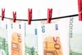 Banknotes hanging on a clothesline against white background. Euro money with red clothes pegs on rope. Money Laundering euro hung Royalty Free Stock Photo
