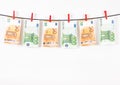 banknotes hanging on a clothesline against white background. Euro money with red clothes pegs on rope. Money Laundering euro hung Royalty Free Stock Photo