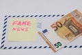 Banknotes on a postal envelope on a light background. Fake news sticker on the envelope. Corrupt journalism. Fake news.