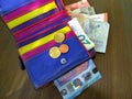 Banknotes and three euro coins in a colorful leather wallet