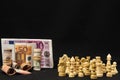 Banknotes and white chess pieces with a black background -  money and power concept Royalty Free Stock Photo