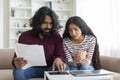 Bankruptcy concept. Overwhelmed millennial indian couple sitting on couch