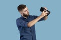 Bankruptcy, poverty and unemployment. Miserable young man looking into empty wallet without money over blue background Royalty Free Stock Photo