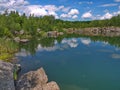 The banks of the lake are lined with large stone blocks in which the white clouds are reflected on the blue sky Royalty Free Stock Photo