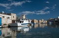 The banks of the Mazaro River in Mazara del Vallo, Italy. The houses are reflected in the water. A boat is moored on the shore.